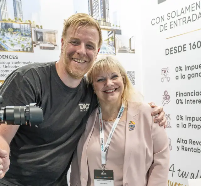 Videógrafo de DKZ Studio con cámara posando junto a una profesional del sector en un stand de feria inmobiliaria · DKZ Studio, Murcia